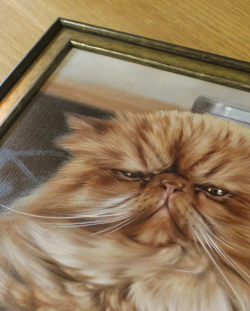 Framed cat oil portrait of Puff displayed on a wall.
