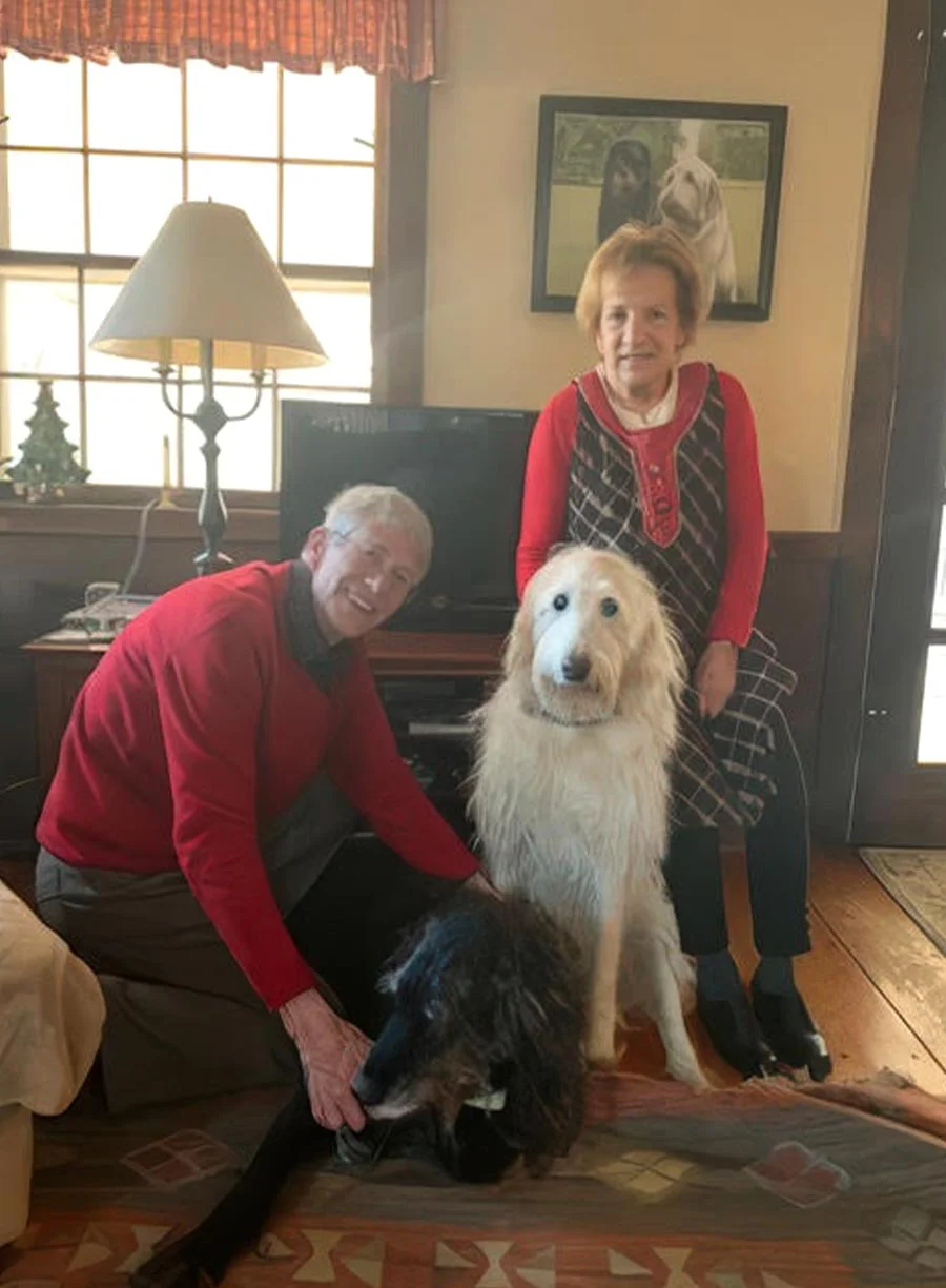 Clients happy with their two-dog oil portrait featuring a custom background by Nicholas Beall Two dogs, a Beagle and another breed, featured in a detailed oil portrait with a background, held by happy clients.