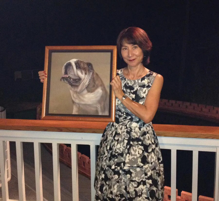 Oil portrait of bulldog Remington successfully delivered to clients in Hawaii A happy client holding a framed oil portrait of their bulldog, Remington, in a beautiful outdoor setting in Hawaii.