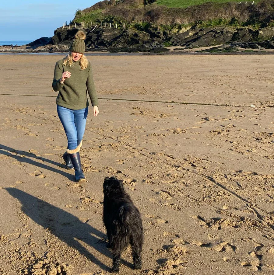 Melanie Phillips and Lily the Tibetan Terrier walking along a serene beach in West Wales during winter.