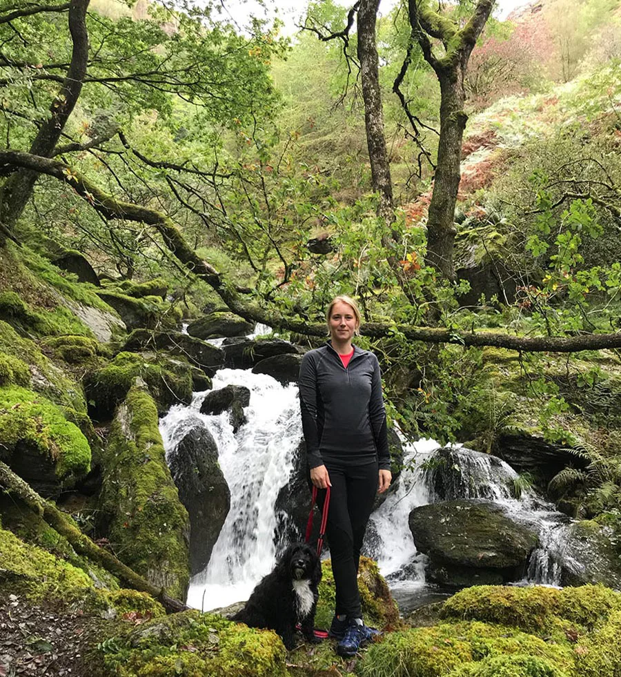 Melanie Phillips trail running on a peaceful woodland path in West Wales.