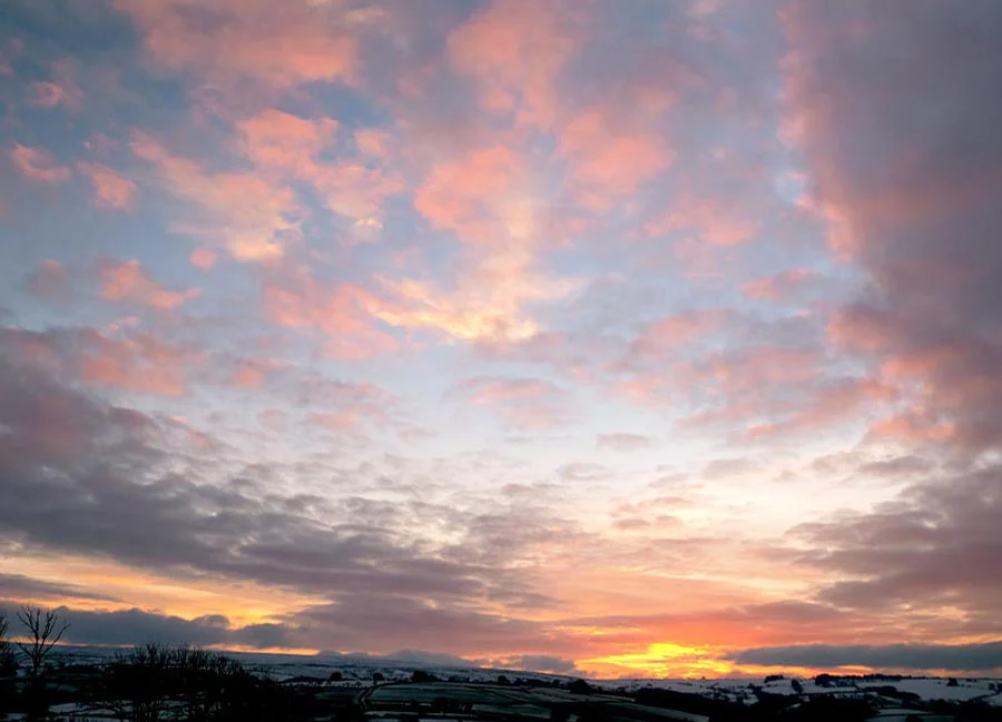 A serene cloudscape photograph by Melanie Phillips, showing soft, layered clouds against a peaceful early morning sky.