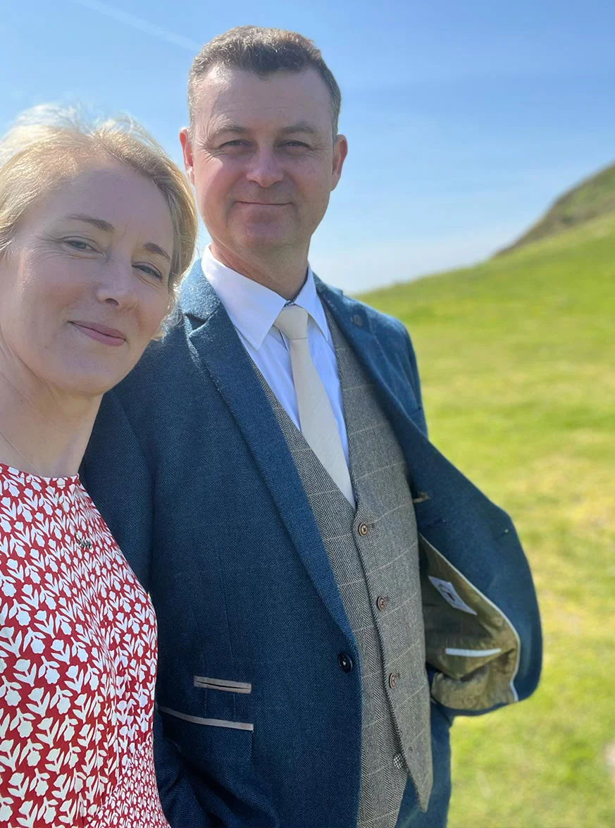 Nicholas Beall smiling at a wedding in Mwnt, West Wales, with the coast in the background.