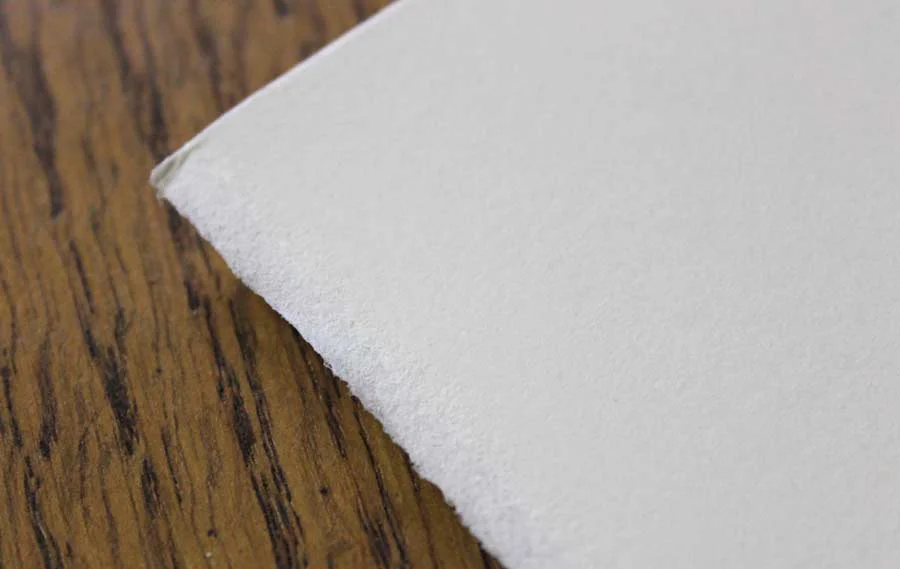 Fabriano Paper with Deckled Edges for Pencil Drawings A close-up of high-quality Fabriano paper, showcasing its characteristic deckled edge and smooth, hot-pressed surface ideal for pencil portraits.